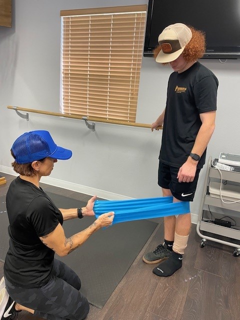 Person with blue elastic bands around knees undertension to form resistance